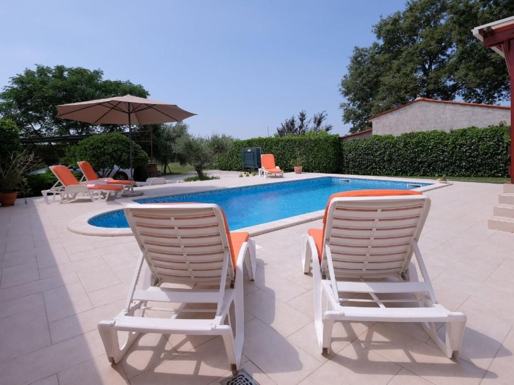 Une piscine avec des chaises longues et une pergola.
