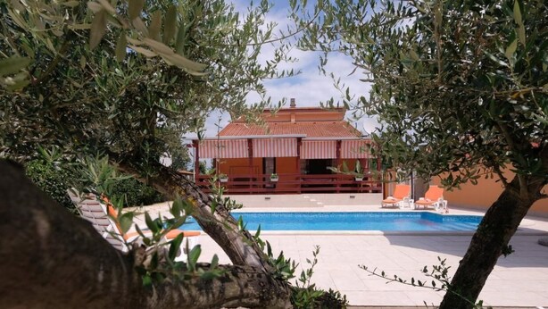 A pool area with a building in the background, surrounded by olive trees. - mit Pool by Interhome (Medulin/Ližnjan)