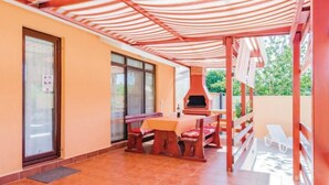 A patio area with a table and benches, a barbecue grill, and a covered seating area. - mit Pool by Interhome (Medulin/Ližnjan)