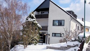 A modern two-story building with a balcony, surrounded by snow-covered trees and a clear sky. - Haus Starkenburg by Interhome (Irmenach)