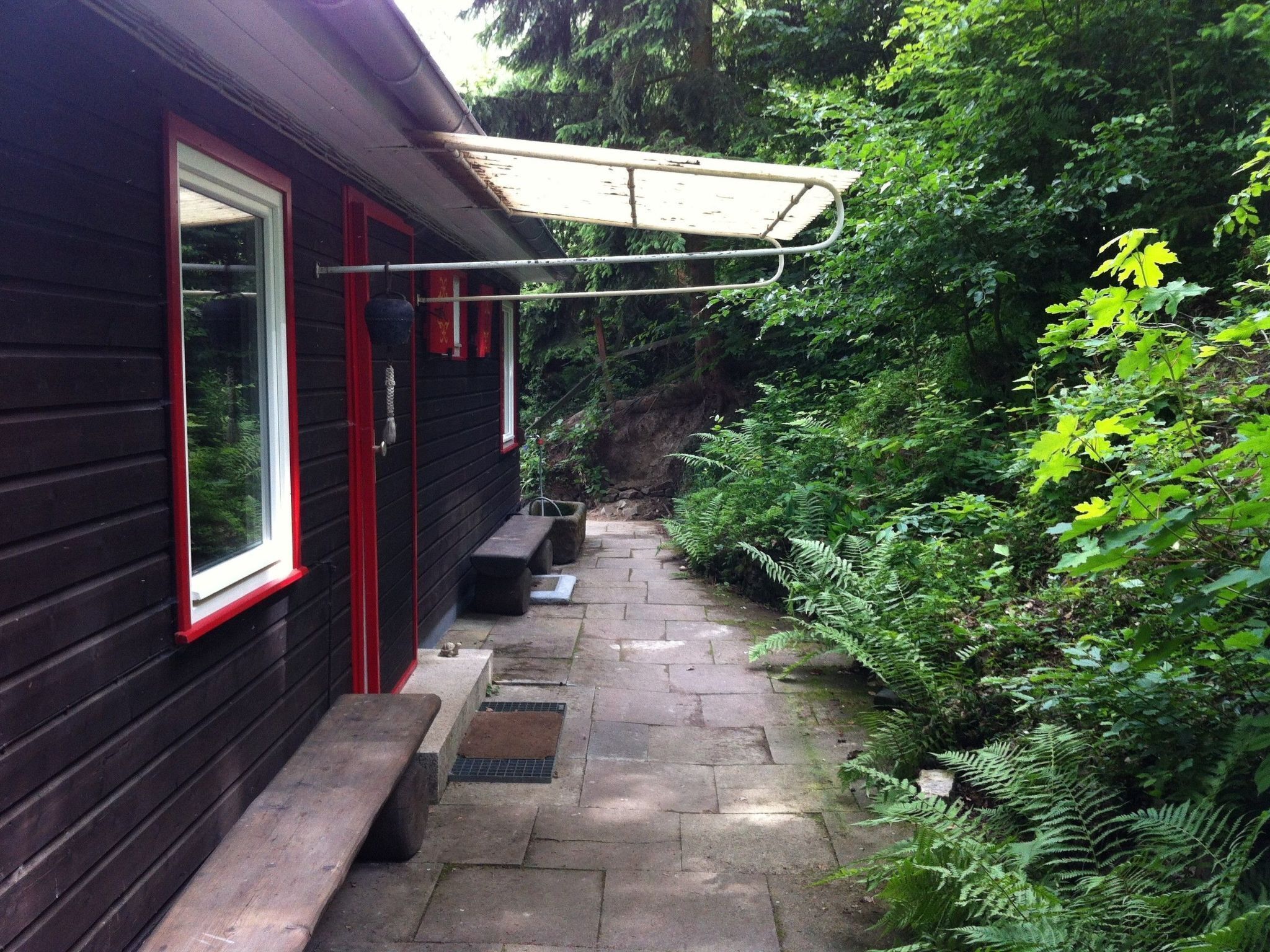 A wooden cabin with a red door, a window, and a bench outside.