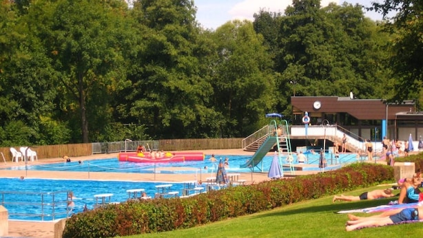 Ein Schwimmbad mit Wasserrutsche, Liegestühlen und einem Rettungsturm.