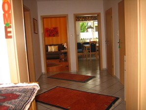 Un pasillo con sofá, zona de comedor, puertas de madera y alfombra.