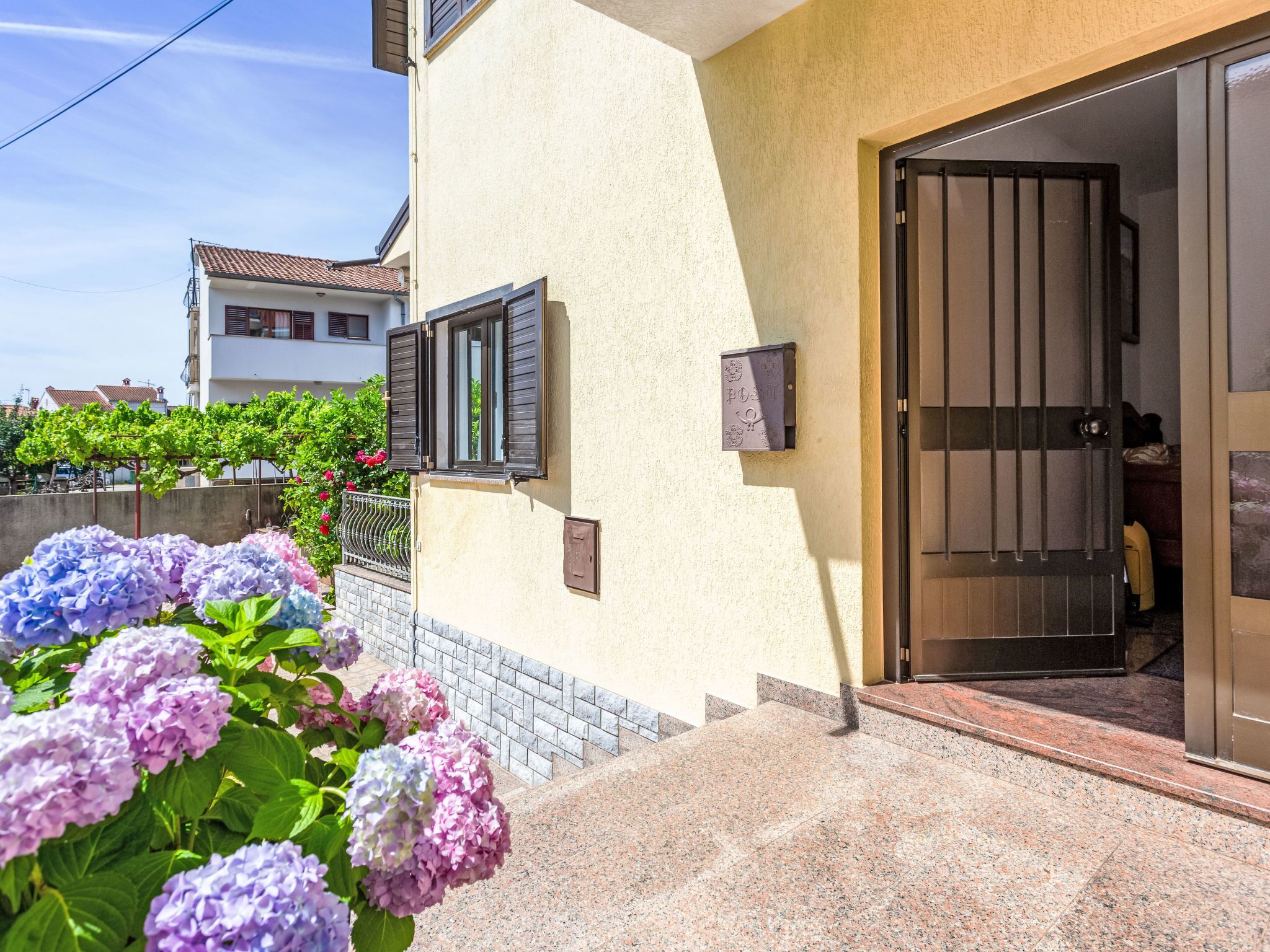 A house with a tiled entrance, a mailbox, and a door with a metal gate.