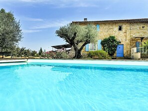 A pool with clear blue water, a stone building with blue shutters, and a large tree in the foreground. - Mas Nouvel by Interhome (Servas)