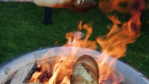 Una griglia con salsicce che cuociono su fuoco vivo.
