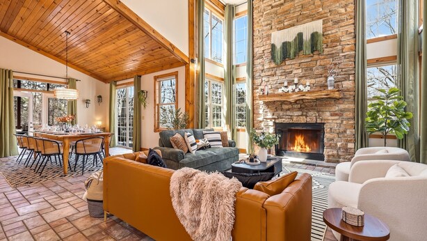 A spacious living room with a fireplace, large windows, and a dining area.