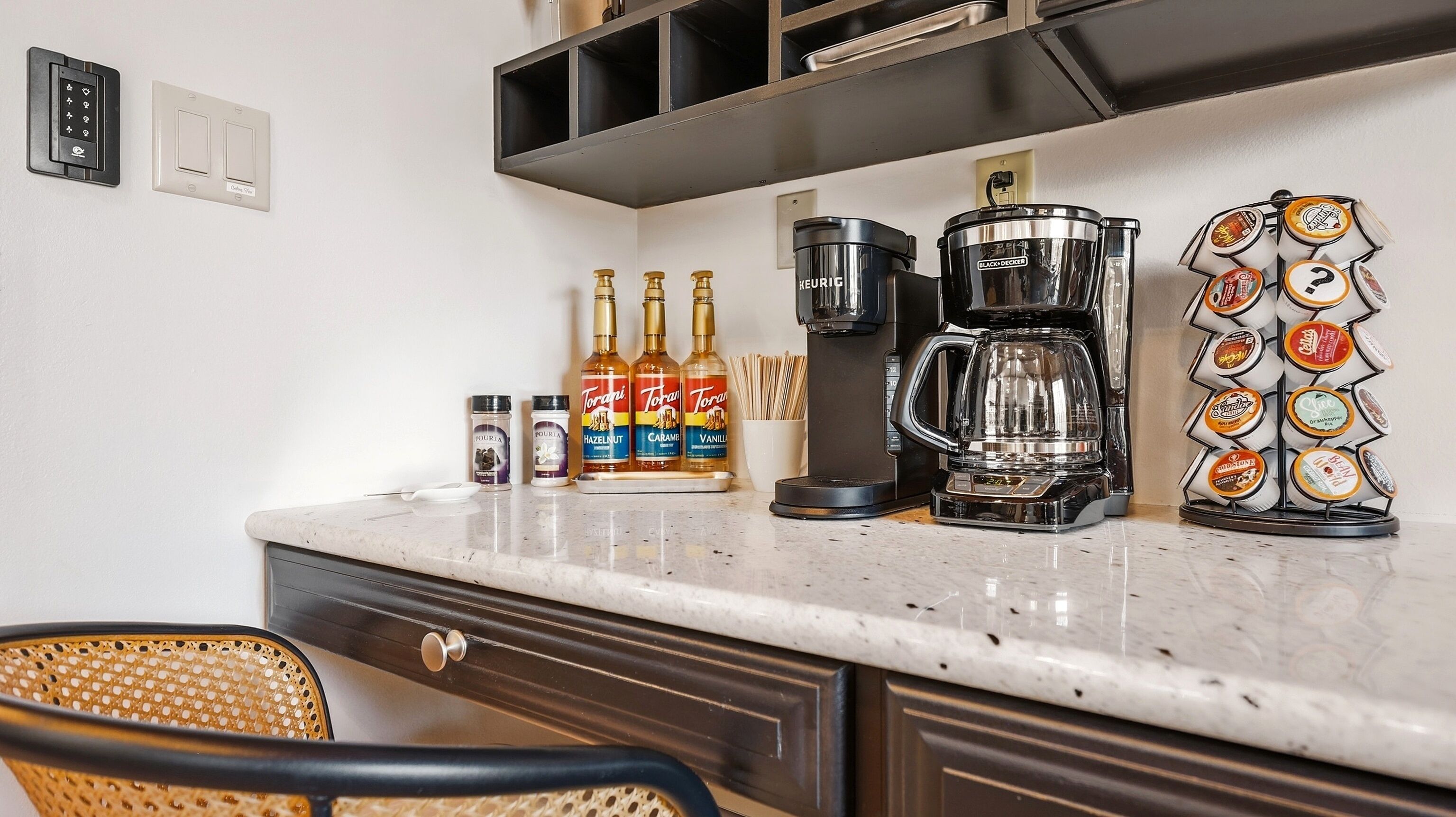 A kitchen with a coffee maker, Torani syrup bottles, and a coffee pod holder.
