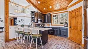 A kitchen with a central island, dark cabinets, and a wooden ceiling.
