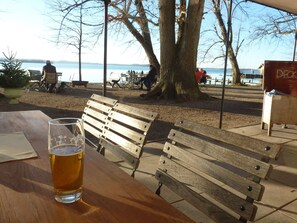 A wooden bench and a glass of beer at a lakeside table. - Haus Monika by Interhome (Übersee)