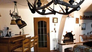 Een gezellige woonkamer met een houten eettafel, stoelen, een open haard en een kroonluchter.