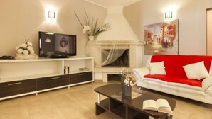 Un salón moderno con un televisor de pantalla plana, un sofá rojo, una mesa de centro y una chimenea.