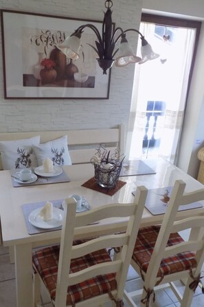 A dining area with a white table, plaid chairs, a chandelier, and a framed picture on the wall. - Bergschlössl in Oberaudorf by Interhome (Oberaudorf)
