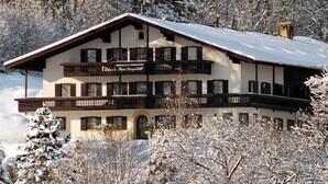 Eine zweistöckige Chalet mit Balkon, umgeben von schneebedeckten Bäumen.
