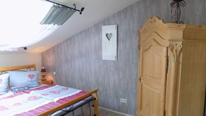 Ein Schlafzimmer mit Bett, Schrank, Deckenventilator und Wandleuchte.