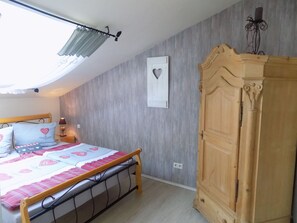 A bedroom with a bed, a wardrobe, a ceiling fan, and a wall-mounted light fixture. - Bergschlössl in Oberaudorf by Interhome (Oberaudorf)