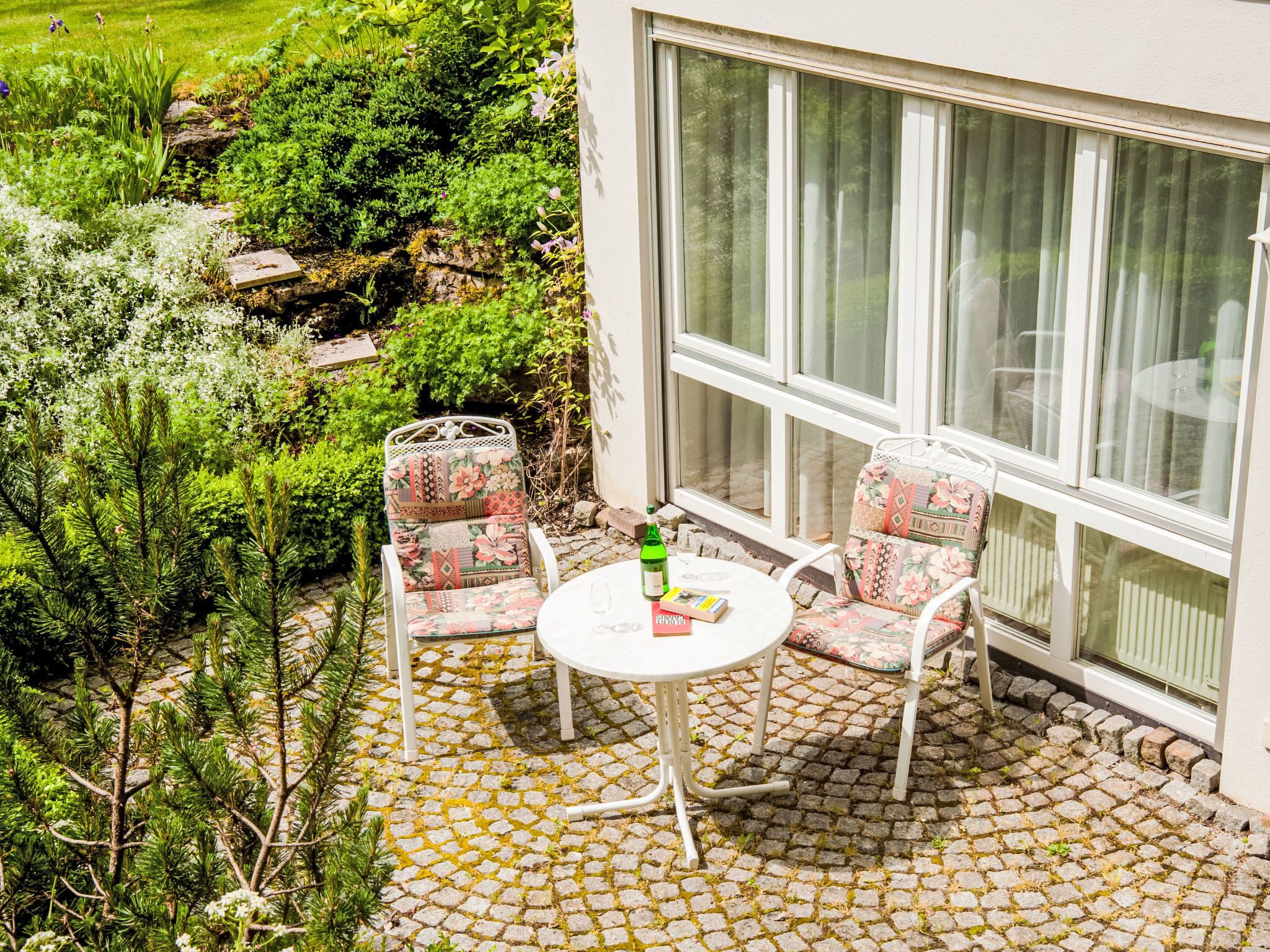 Une terrasse avec une table et des chaises, une bouteille et un livre.