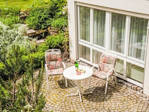 Une terrasse avec une table et des chaises, une bouteille et un livre.