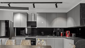 Una cocina moderna con encimera de mármol, electrodomésticos de acero inoxidable y un comedor con mesa de mármol y sillas acolchadas.