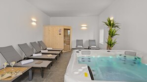 Un cuarto de spa con hidromasaje, sillones de descanso y sauna.