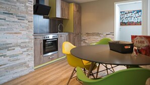 Una cocina moderna con horno empotrado, un fregadero y una estufa. Hay una mesa de comedor con sillas y una cesta encima.