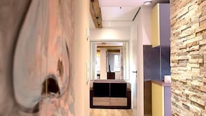 Een moderne hal met houten vloeren, een accentmuur van steen en een inbouwspots.