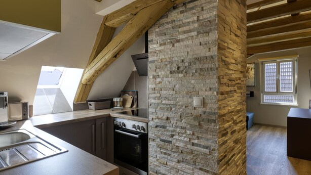 Een moderne keuken met een stenen muur, houten balken en dakramen.