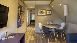 Een modern interieur met een eethoek, bestaande uit een ronde tafel en stoelen, een wandgemonteerde flatscreen televisie en houten balken aan het plafond.