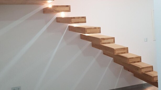 Una escalera moderna con escalones de madera e iluminación integrada.