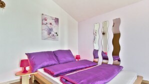 Quarto moderno com uma cama grande, duas mesas de cabeceira e um espelho decorativo.