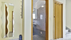 Um corredor com um banheiro visível através de uma porta aberta.