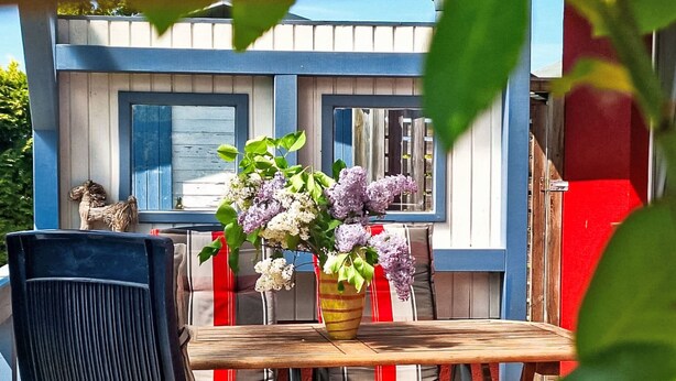 Ein Holztisch mit Stühlen, eine Vase mit Blumen und eine kleine Hundestatue.