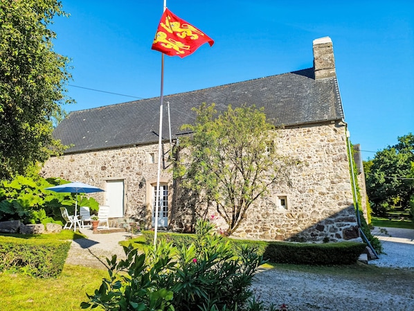 Un bâtiment en pierre avec un mât de drapeau, une porte et une fenêtre.