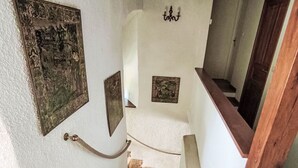 En trappe med gelænder, en vægmonteret lampe og billeder i rammer.