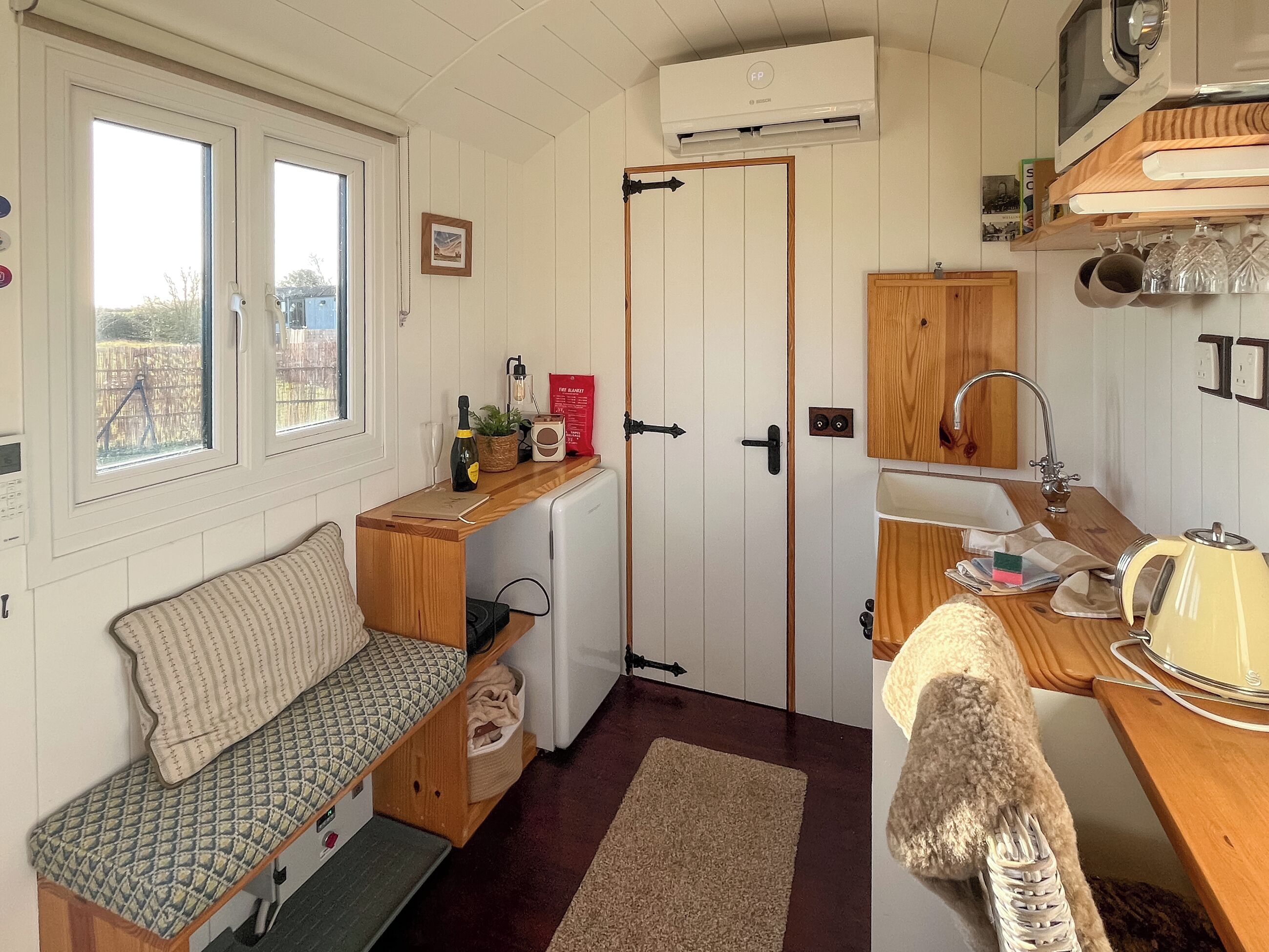 A compact kitchen with a built-in fridge, a sink, a microwave, and a wooden counter.