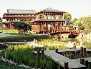 Il s'agit d'un bâtiment de style japonais traditionnel, doté d'une structure en bois, d'un pont enjambant un étang et d'un jardin bien entretenu avec une terrasse en bois.
