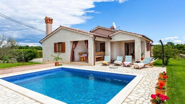 Una casa a due piani con piscina, area salotto all'aperto e giardino.
