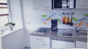 Une cuisine moderne équipée d’un four à micro-ondes, d’une machine à café et d’ustensiles suspendus.