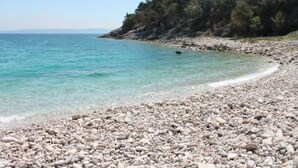 A pebble beach with clear turquoise water and a rocky shoreline. - Casa Mia mit privatem Pool by Interhome (Barban)