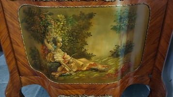 A wooden cabinet with a glass top, featuring a painted landscape scene.
