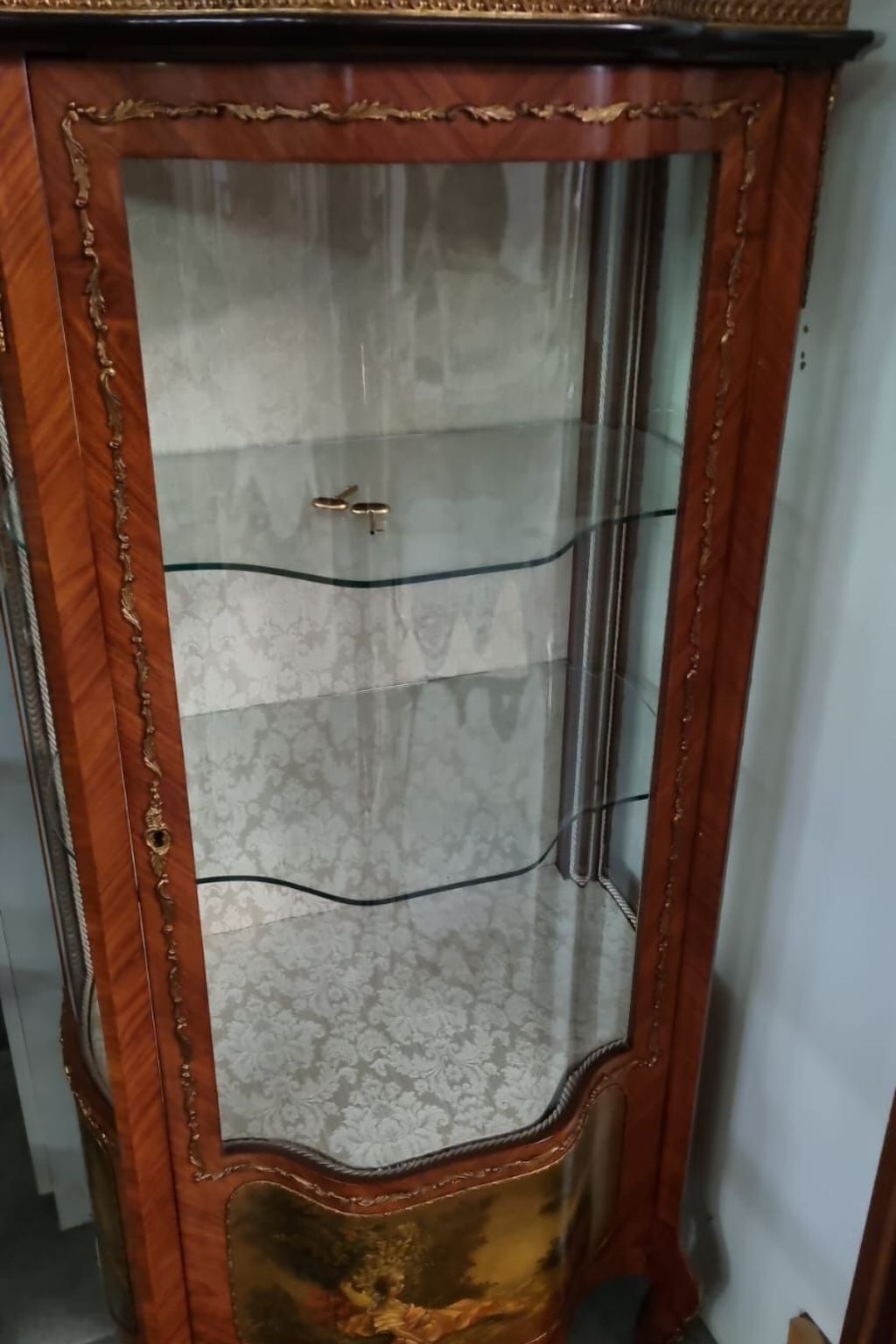 A tall, ornate wooden cabinet with glass doors and a gold handle.