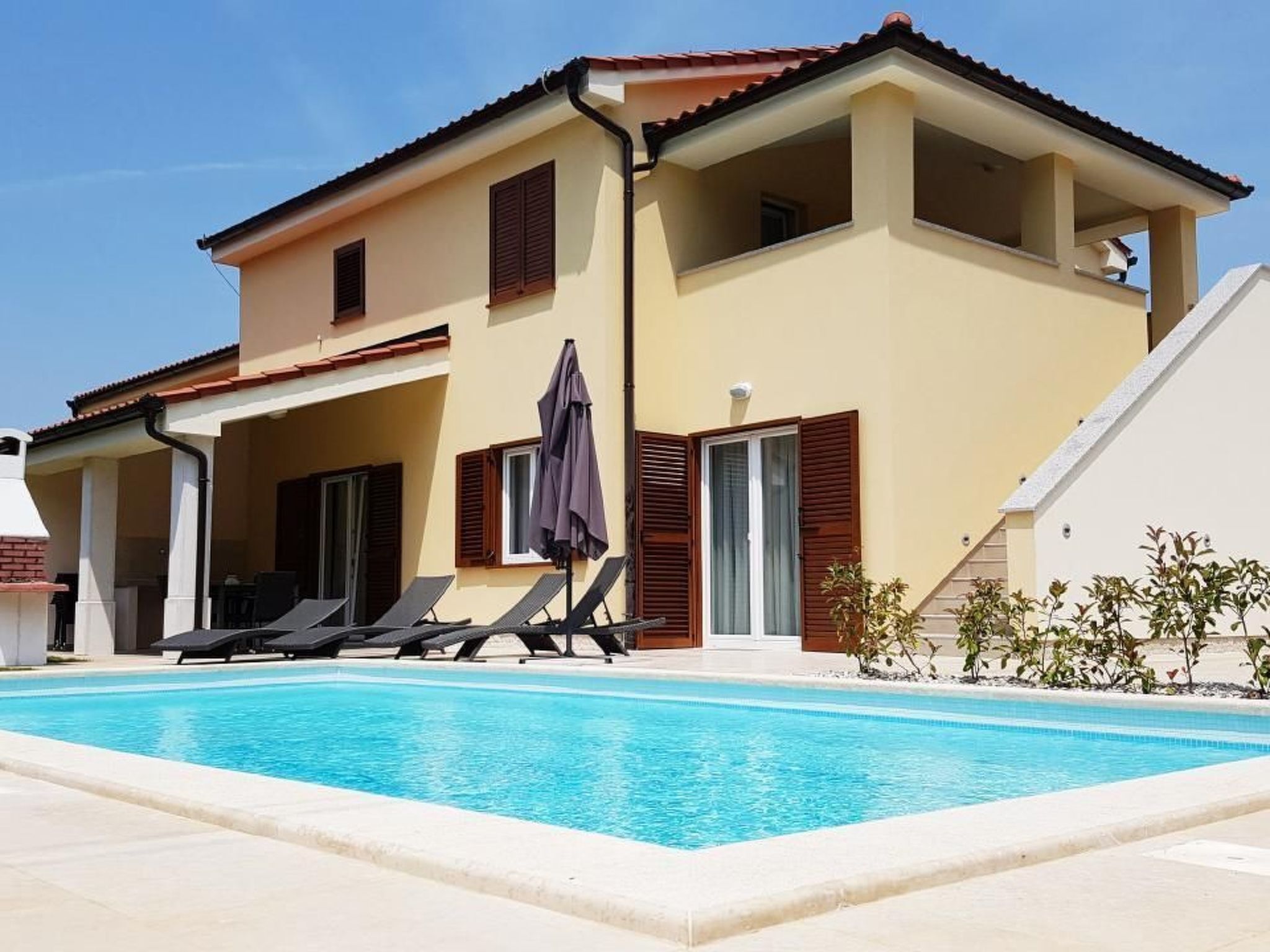 Un edificio a due piani con piscina, area salotto all'aperto e patio coperto.