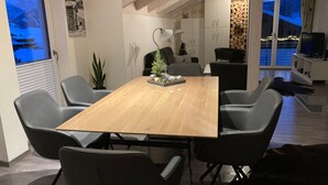 A dining area with a wooden table and grey chairs, a small Christmas tree, and a view of the outside through a large window. - Fewo Bergblick lodge by Interhome (Ofterschwang)