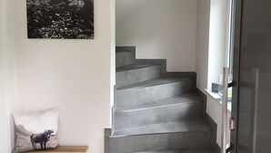 A staircase with a minimalist design, a wall-mounted painting of a mountain landscape, and a cushion with a cow design. - Fewo Bergblick lodge by Interhome (Ofterschwang)