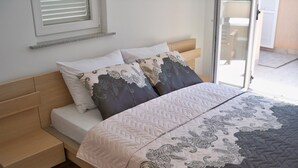 A bedroom with a bed, two pillows, a bedside table, and a window with blinds. - Apartment mit Balkon für zwei bis vier Personen by Interhome (Pula/Banjole)