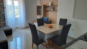 A dining area with a table, chairs, a bowl, a TV, and a shelf with items. - Apartment mit Balkon für zwei bis vier Personen by Interhome (Pula/Banjole)