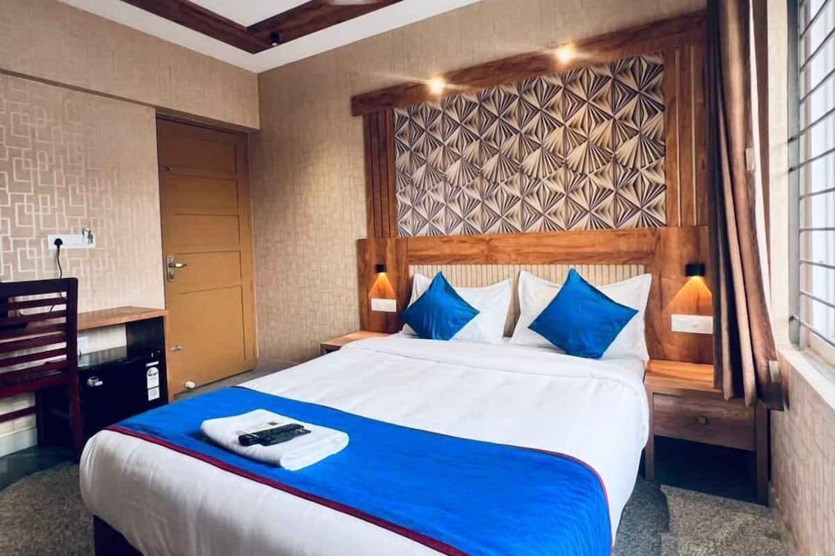 Une chambre d’hôtel avec un grand lit, un bureau et une fenêtre avec des rideaux.
