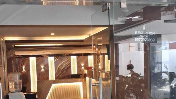 A reception area with a marble floor and glass doors, a reception desk, and a motorcycle parked outside. - Celestial Heights (Kanayannur)