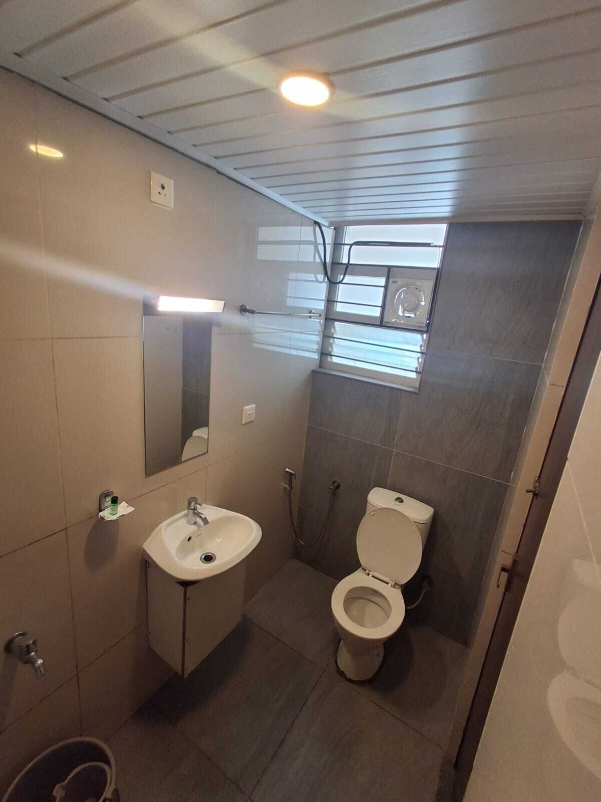 Un baño pequeño y moderno con lavamanos, espejo, inodoro y ducha.