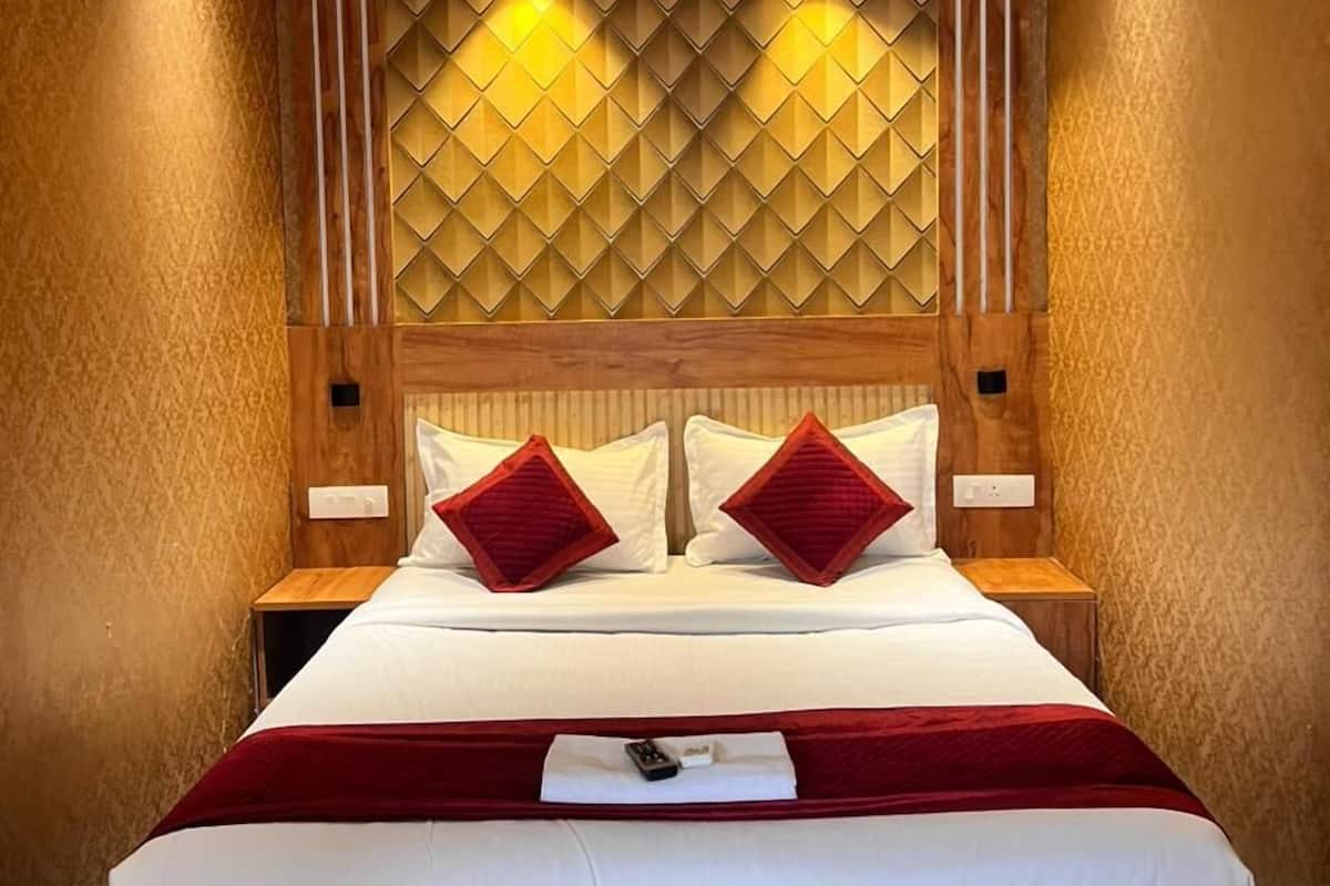 Une chambre d’hôtel avec un lit, une tête de lit en bois, deux tables de chevet et un ventilateur de plafond.